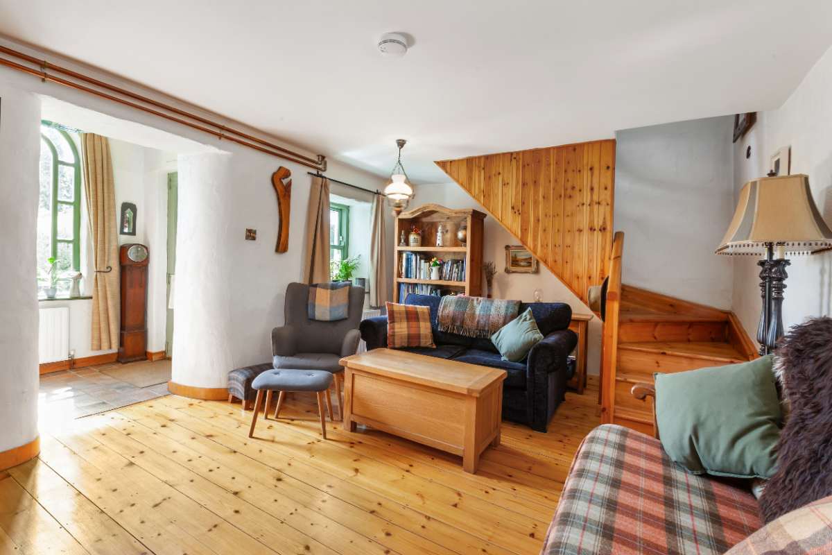 Sitting room with pine staircase and arched window beyond
